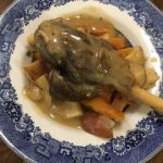 Braised Goat Shank on potatoes and carrots covered in gravey