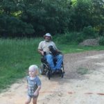 Cooper running from daddy, Randy in his wheelchair with dog Georgia in his lap