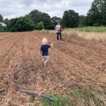 Jo spreading cover crop seed, Cooper helping