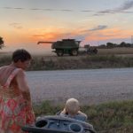 Grammy G and Cooper watching soy bean harvest at sunset