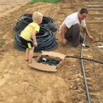 Cooper helping Josephine hook up irrigation