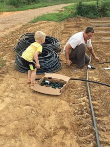 Cooper helping Josephine hook up irrigation