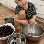 Cooper squeezing the sweet middle out of muscadines for jam making