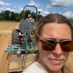 Josephine taking a selfie with Randy on the tractor shaping beds for spring