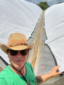 Josephine just finished lacing rope to secure the shade cloth on the double bay high tunnel