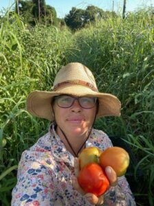Farmer Josephine selfie holding freshly harvested tomatoes deep in the tomato jungle