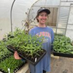 Meg holding some native plants that will be for sale in May