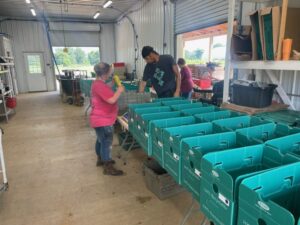 Kayla (L) and Robin (R) packing CSA shares with Connie in the background weighing out potatoes.