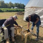 Randy (L) and Robin (R) cutting poles as they work on repairing a high tunnel