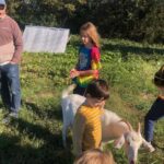 David (L), Oscar (Middle background), Ca;lvin (front center) and Cooper (R) and others spending a moment with our goat, Peanut