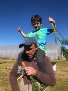 David with Calvin on his shoulders enjoying fresh picked carrots