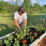 Josephine planting assorted flowers and produce in our tub