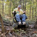 Randy in the EcoRover track chair going over downed trees