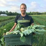 Patrick holding a crate of kohlrabi in front of our field